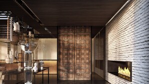 A modern interior with a brick wall, a fireplace, and a glass table with decorative items. - Roomers Parkview, A Luxury Collection Hotel, Frankfurt (Frankfurt)