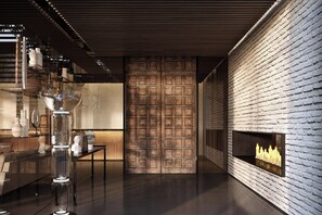A modern interior with a brick wall, a fireplace, and a glass table with decorative items. - Roomers Parkview, A Luxury Collection Hotel, Frankfurt (Frankfurt)