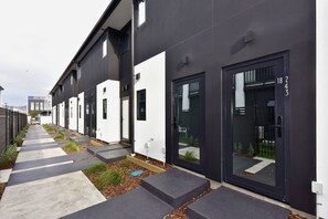 Ein modernes Gebäude mit schwarz-weißer Fassade, nummerierten Türen und einem gut sichtbaren Zugang.
