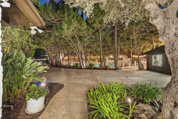 A landscaped outdoor area with a pathway, trees, and a building with large windows.
