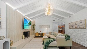 Een ruime woonkamer met een hoge plafond, een grote flatscreen televisie, een bank en een open haard.