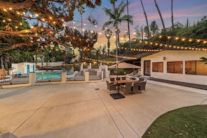 Ein Außenbereich mit Terrasse, Pool, Lichterkette und Gartenmöbeln.