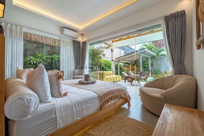 Ein modernes Schlafzimmer mit einem großen Bett, einer Couch und einem Essbereich mit Blick auf den Garten.
