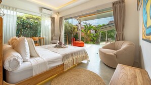A modern bedroom with a large bed, a seating area, and a view of the outdoors.