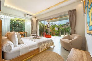 Ein modernes Schlafzimmer mit einem großen Bett, einer Sitzecke und Blick ins Freie.