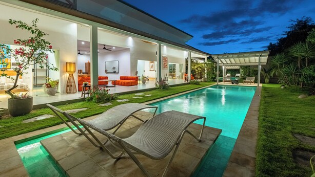 A modern house with a swimming pool, outdoor seating, and a well-maintained garden.