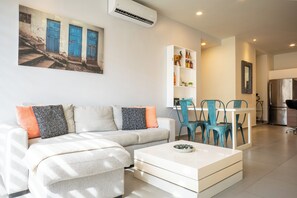 A modern living room with a sofa, coffee table, and a dining area with chairs and a table. - Fabulous 2 bedroom Penthouse condo at Lunada (Playa Del Carmen)
