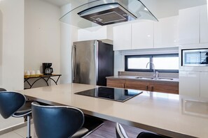 A modern kitchen with a stainless steel refrigerator, a built-in oven, a sink, and a window above the countertop. - Fabulous 2 bedroom Penthouse condo at Lunada (Playa Del Carmen)