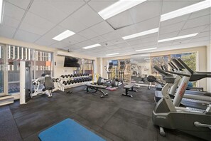 Ein Fitnessstudio mit Laufbändern, Kurzhanteln und Trainingsgeräten.