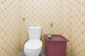 Un baño con inodoro, un cesto de basura y una pared con diseño de diamantes.