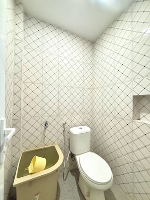 Un baño pequeño con un inodoro, un lavamanos y un cubo de basura.