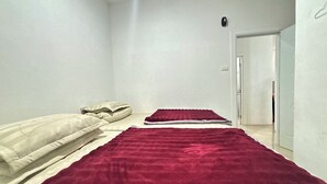 Une chambre à coucher avec un lit, une couverture rouge et un mur blanc.