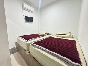A small, clean room with two beds, a TV, and an air conditioning unit. - Hotel O Medina House (Banda Aceh)
