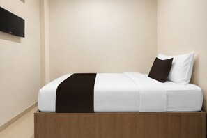 Una cama bien hecha con un edredón blanco y negro, un cabecero de madera y una única almohada blanca.