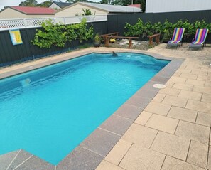 Ein rechteckiger Pool mit einer gefliesten Kante, umgeben von einer Ziegelterrasse.
