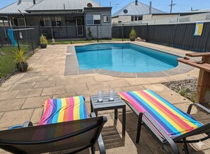 Ein Garten mit Schwimmbecken, Liegestühlen und einem Tisch mit Gläsern.