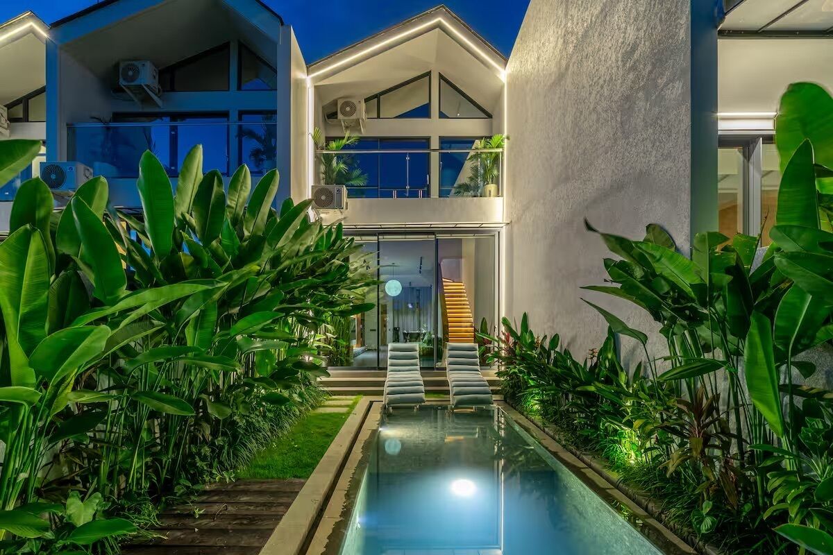 Una casa moderna con piscina, rodeada de abundante vegetación.