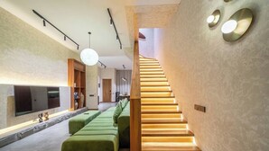 Un interior moderno con una escalera, asientos verdes y un televisor de pantalla plana.