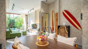 Un comedor moderno con una mesa de madera, un sofá verde y vistas a una piscina.