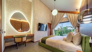 Una habitación de hotel moderna con una cama verde, un escritorio con silla, un espejo grande y un televisor.
