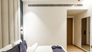 Una habitación de hotel moderna con una cama grande, un ventilador de techo y un espejo amplio.
