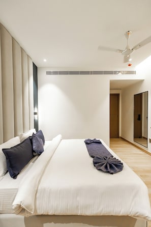 A modern hotel room with a large bed, a ceiling fan, and a large mirror.