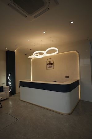 A reception desk with a sign reading 'The Modern Sarai,' a curved counter, and a modern light fixture.