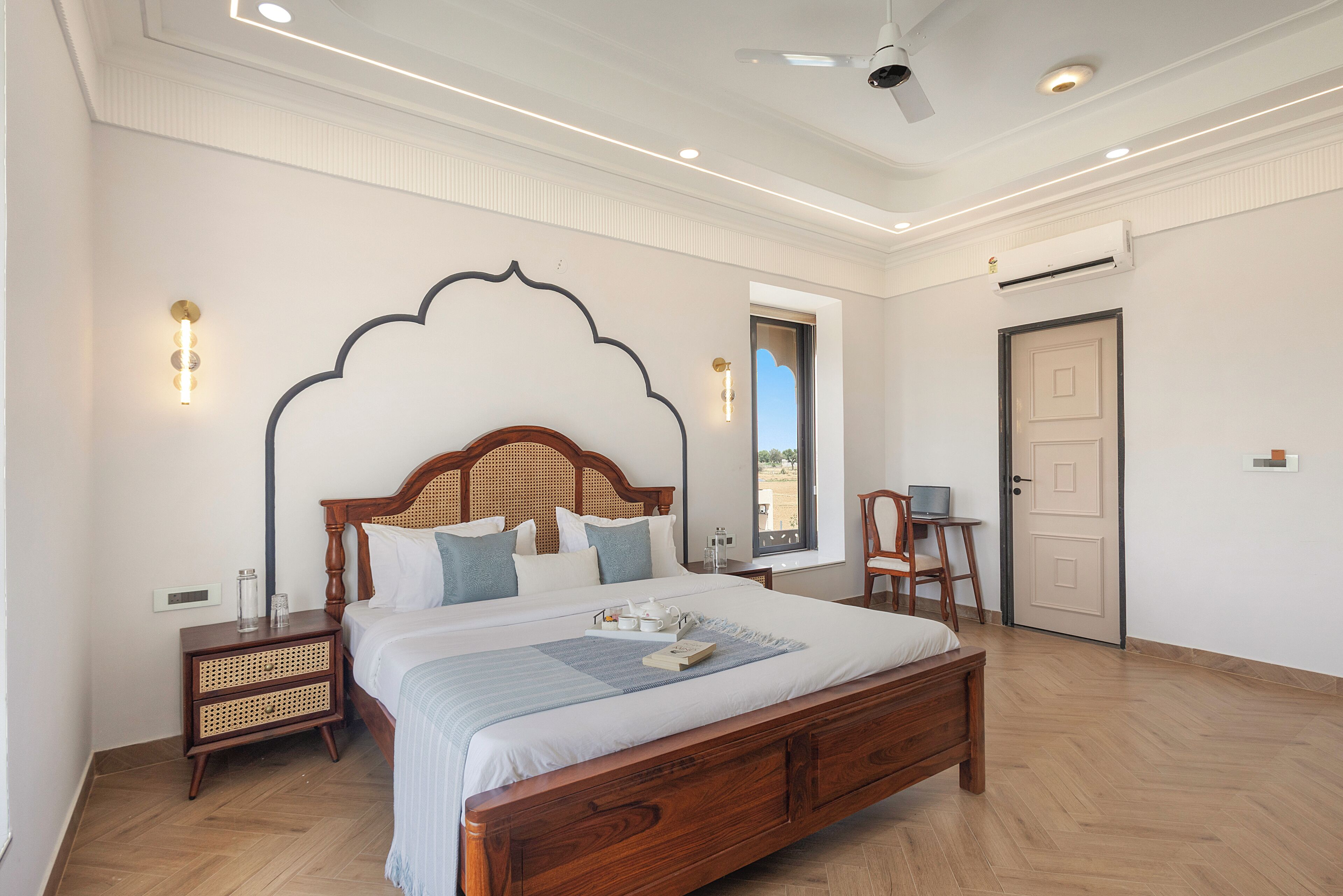 A bedroom with a wooden bed, bedside tables, a desk, and a view of the outside.