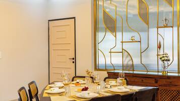 A dining room with a table set for four, chairs, a door, and a decorative window with a view.