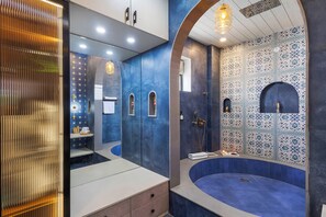 A modern bathroom with a large mirror, a bathtub, and a vanity with drawers. - ELIVAAS Nirvana 5BHK Farmhouse with Pool (Amer)