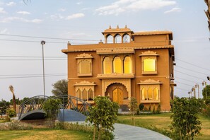 A traditional building with a large entrance, multiple windows, and a bridge in the foreground. - ELIVAAS Nirvana 5BHK Farmhouse with Pool (Amer)