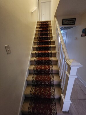 Eine Treppe mit Teppichstufen, einem Geländer und einem Schild mit der Aufschrift 'LIVE LAUGH LOVE'.