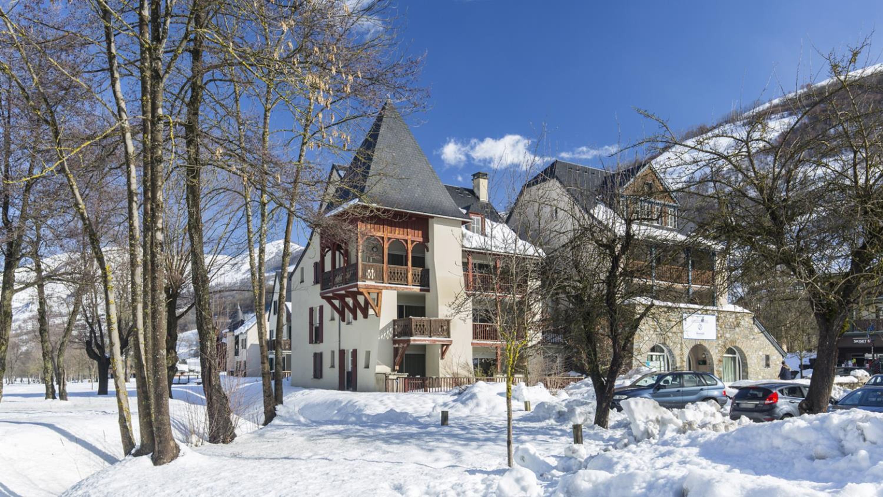 Ein mit Schnee bedecktes Gebäude mit einem steilen Dach, hölzernen Balkonen und einer Stein-Fassade.