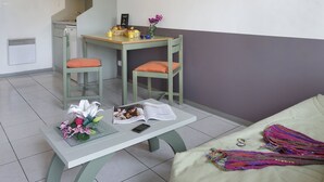 Un espacio habitable compacto con kitchenette, comedor y sofá.