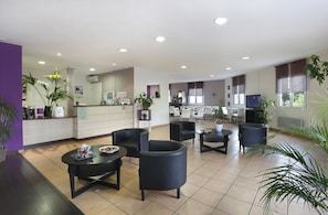 A spacious lobby with a reception desk, seating area, and a television. - R Sidence R sid Price St2s (Merville)