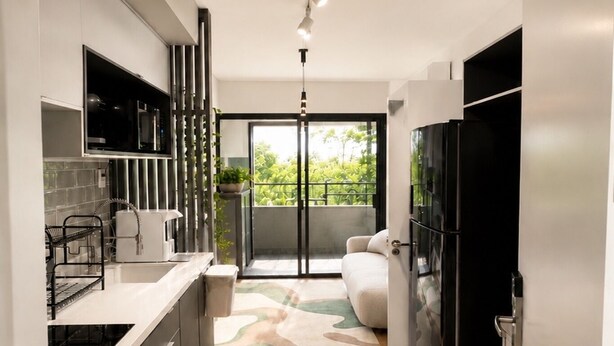 Eine moderne Küche mit einer zentralen Kochinsel, integrierten Geräten und einer Schiebeglastür zum Balkon.