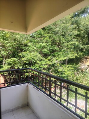 Ein Balkon mit Metallgeländer, der einen dichten, grünen Wald überblickt.
