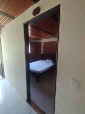 Ein Zimmer mit einem Bett, einer Holzbalkendecke und einer Backsteinwand.