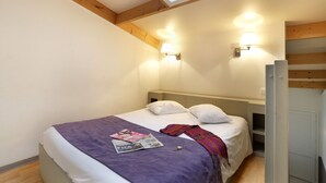 A bedroom with a bed, two wall-mounted lights, a skylight, and a magazine on the bed. - R Sidence R sid Price St6n (Merville)