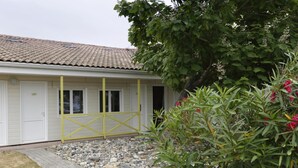 A building with a tiled roof, a yellow gate, and a garden with rocks and plants. - R Sidence R sid Price St6n (Merville)