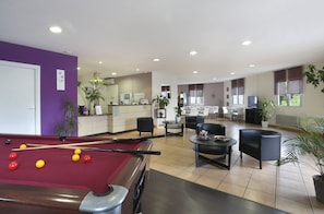 A pool table with balls, a billiards cue, and a red felt surface. There are multiple chairs and tables in a room with a tiled floor. - R Sidence R sid Price St4n (Merville)
