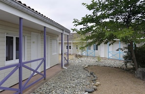 A row of white buildings with purple accents, a gravel pathway, and a tree. - R Sidence R sid Price St4n (Merville)