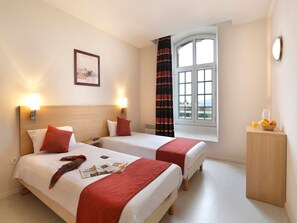 A hotel room with two beds, a window with curtains, a bedside table with a fruit bowl, and a wall-mounted picture. - Les Demeures Champenoises 2p4s (Epernay)