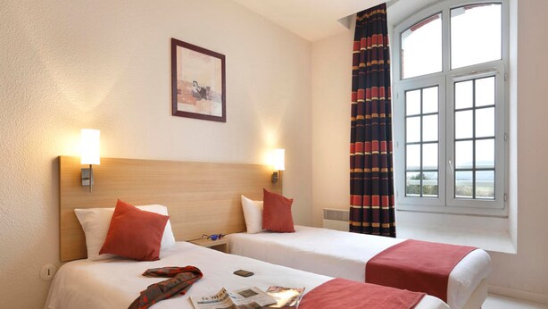 Habitación de hotel con dos camas, una ventana con cortinas, un cuadro en la pared y una lámpara en la mesita de noche.