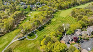 Luchtbeeld van een woongebied met huizen, een golfbaan en een waterpartij.