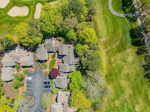 Oversigtsbillede af et boligområde med huse, parkeringsplads og grøn bevoksning omkring.