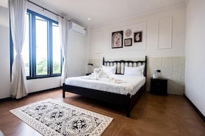 Ein Schlafzimmer mit einem Bett, einem Nachttisch, einem Fenster mit Vorhängen und einem gemusterten Teppich.