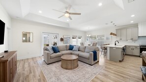 A spacious living area with a sectional sofa, a round coffee table, and a ceiling fan. - Family & Dog-Friendly Home With Golf Cart And Just Steps to Beach (Panama City Beach)