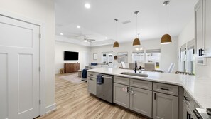 A modern kitchen with a central island, grey cabinetry, and pendant lighting. - Family & Dog-Friendly Home With Golf Cart And Just Steps to Beach (Panama City Beach)
