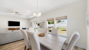 A modern living room with a flat-screen TV, a ceiling fan, and a dining area with a wooden table and chairs. - Family & Dog-Friendly Home With Golf Cart And Just Steps to Beach (Panama City Beach)